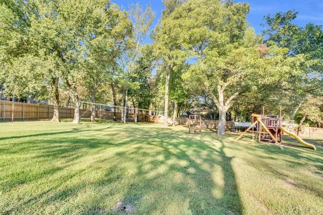 a view of a house with a big yard and large trees
