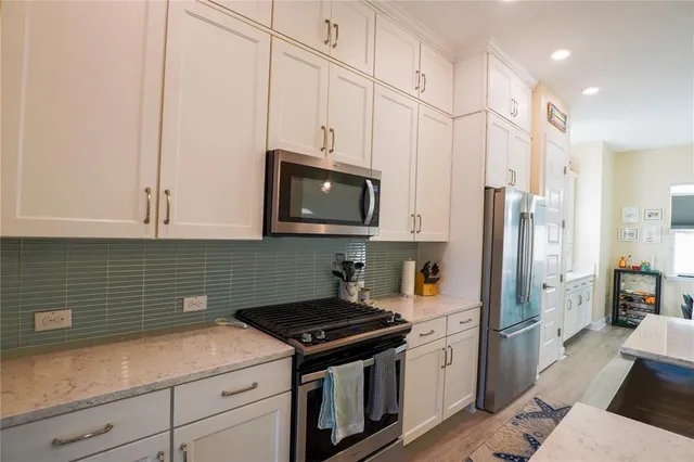 a kitchen with stainless steel appliances kitchen island a refrigerator a stove a sink and chairs
