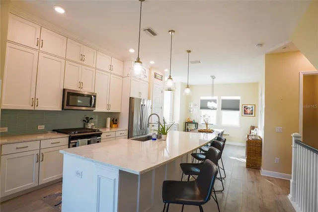 a kitchen with sink a refrigerator and chairs