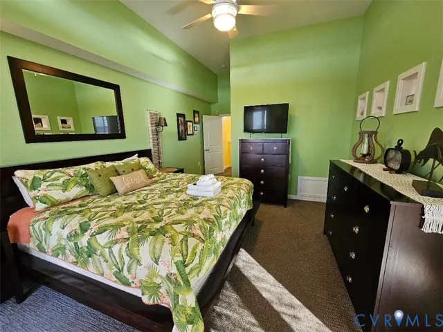 a bed sitting in a bedroom and a flat tv screen on dresser