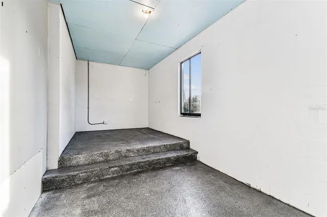 an empty room with wooden floor ceiling fan and windows
