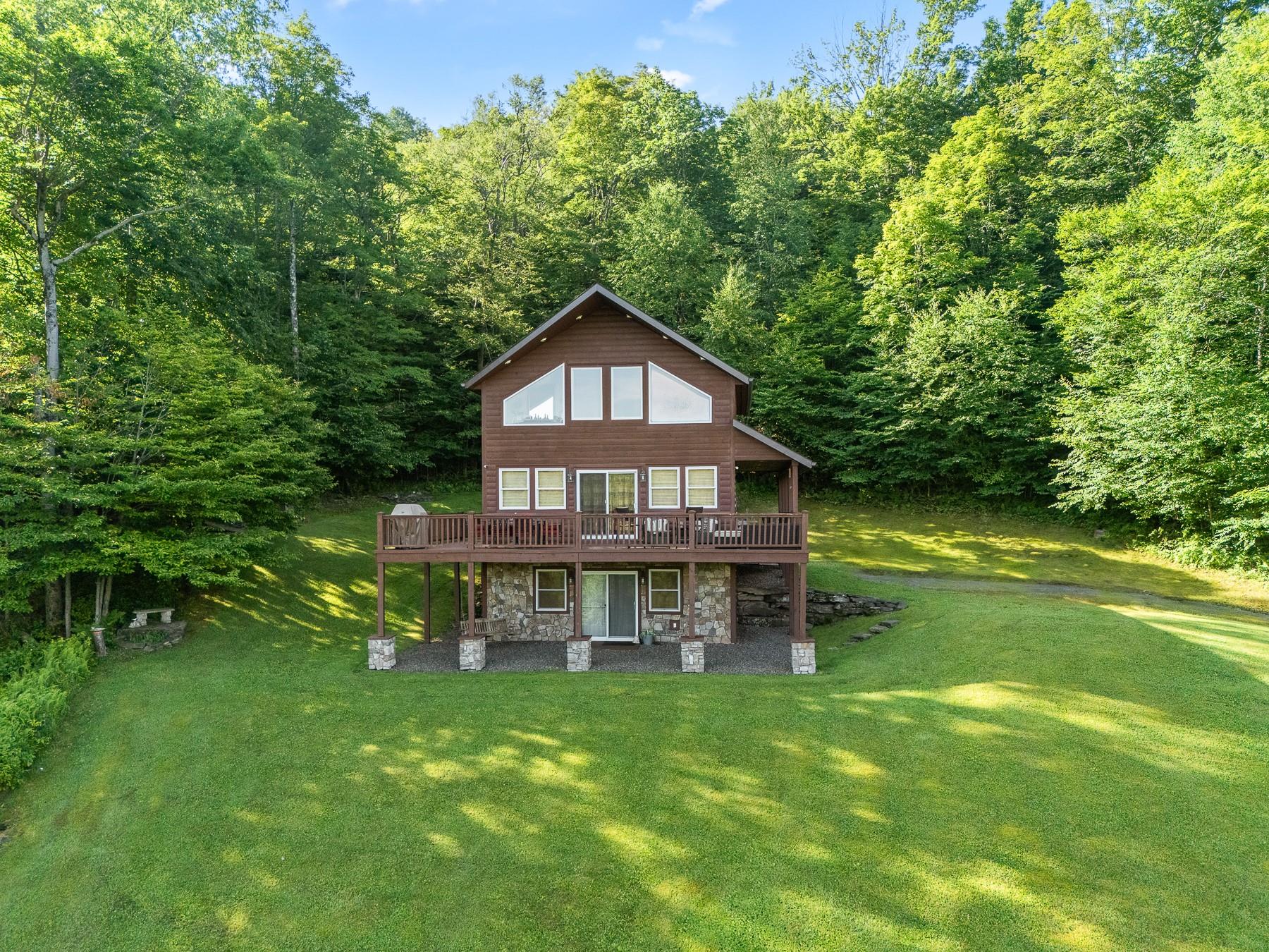 a view of a house with a big yard plants and large trees