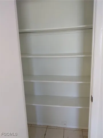 an empty room with windows and chandelier fan