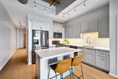 a kitchen with cabinets a sink appliances and chairs