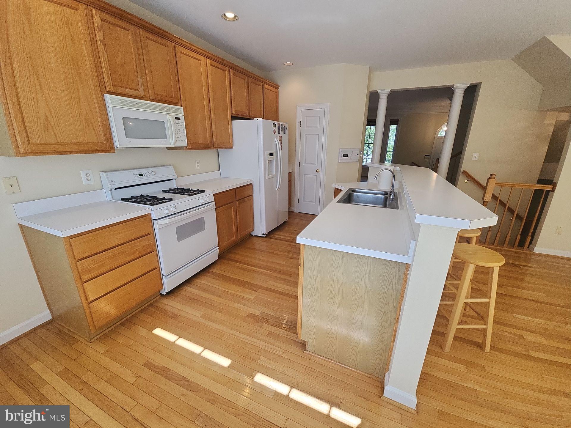 6681 Debra Lu Way Springfield, VA 22150 - Photo 12 of 57 a kitchen with granite countertop a sink a stove top oven a refrigerator and wooden cabinets