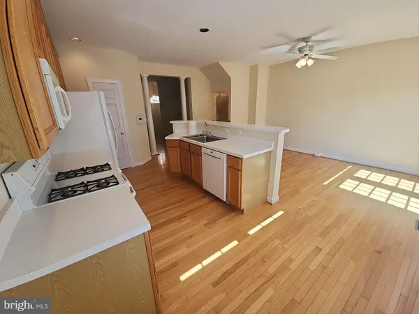 a kitchen with stainless steel appliances a refrigerator a sink a stove a dining table and chairs with wooden floor