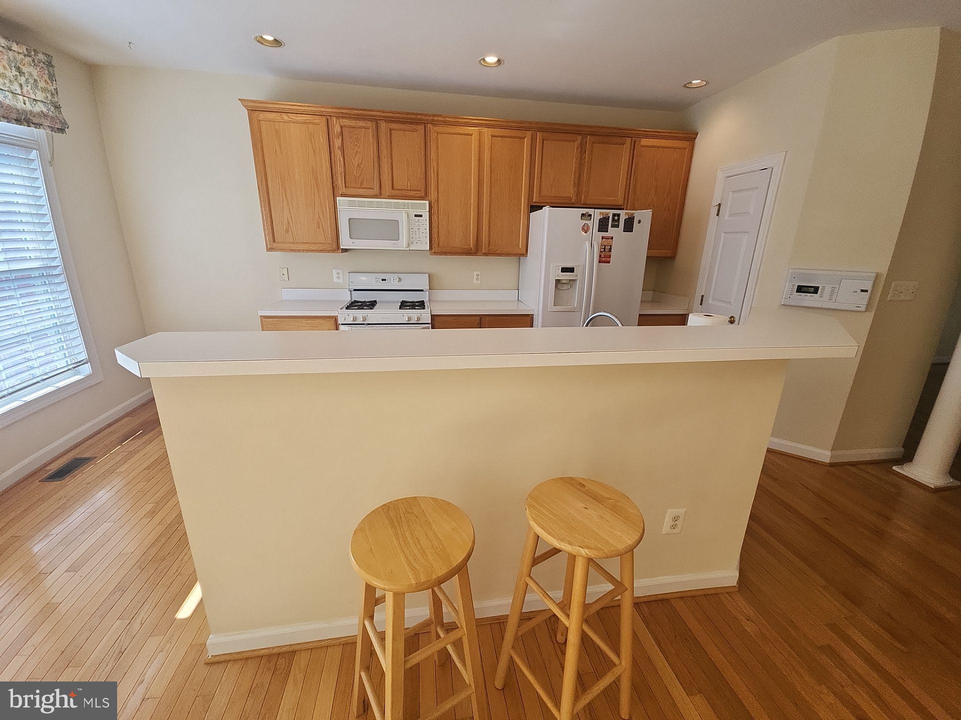 6681 Debra Lu Way Springfield, VA 22150 - Photo 15 of 57 a kitchen with stainless steel appliances a refrigerator a sink a stove a dining table and chairs with wooden floor