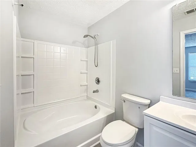 a white toilet and tub sitting next to a bathroom sink