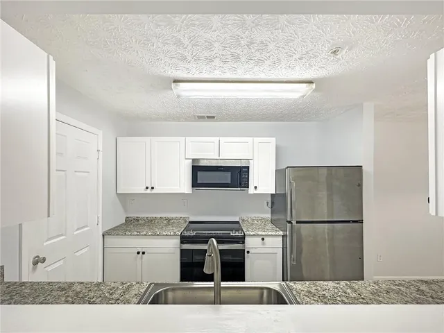 a kitchen with stainless steel appliances granite countertop a refrigerator stove and microwave