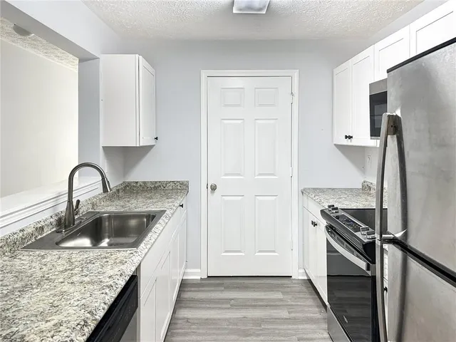 a kitchen with granite countertop stainless steel appliances cabinets a sink and a stove