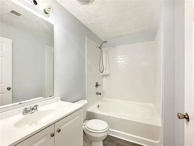 a bathroom with a granite countertop sink a toilet and shower