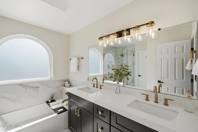 a bathroom with a double vanity sink mirror and bathtub