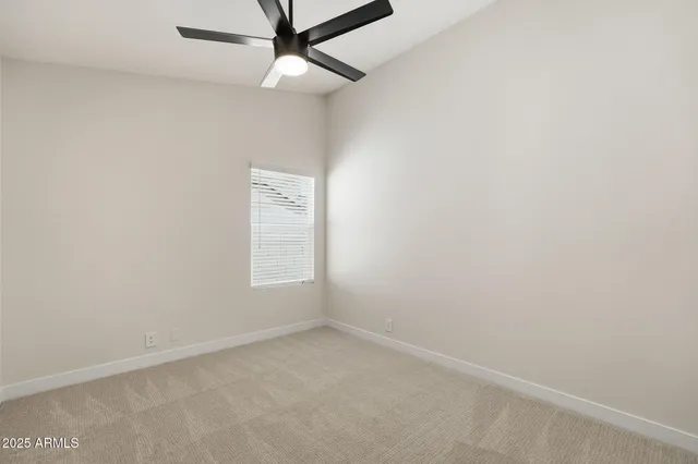 an empty room with a window and ceiling fan