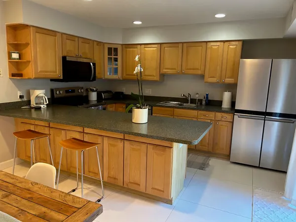 a kitchen with stainless steel appliances granite countertop a refrigerator a stove a sink a counter space and cabinets