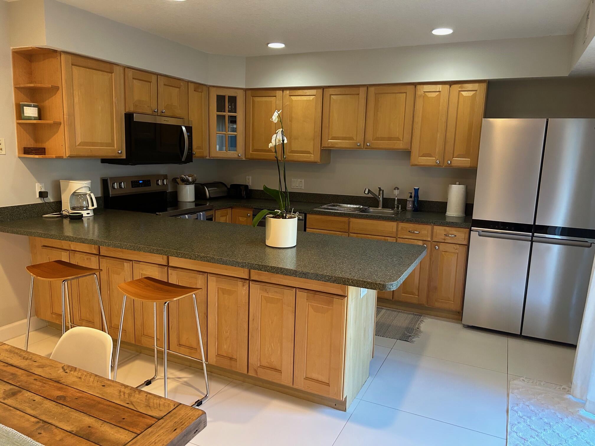 1420 Ocean Way Drive, Unit 32C Jupiter, FL 33477 - Photo 4 of 25 a kitchen with stainless steel appliances granite countertop a refrigerator a stove a sink a counter space and cabinets