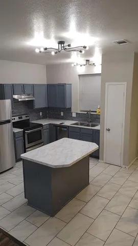 a kitchen with stainless steel appliances granite countertop a stove a sink and a refrigerator