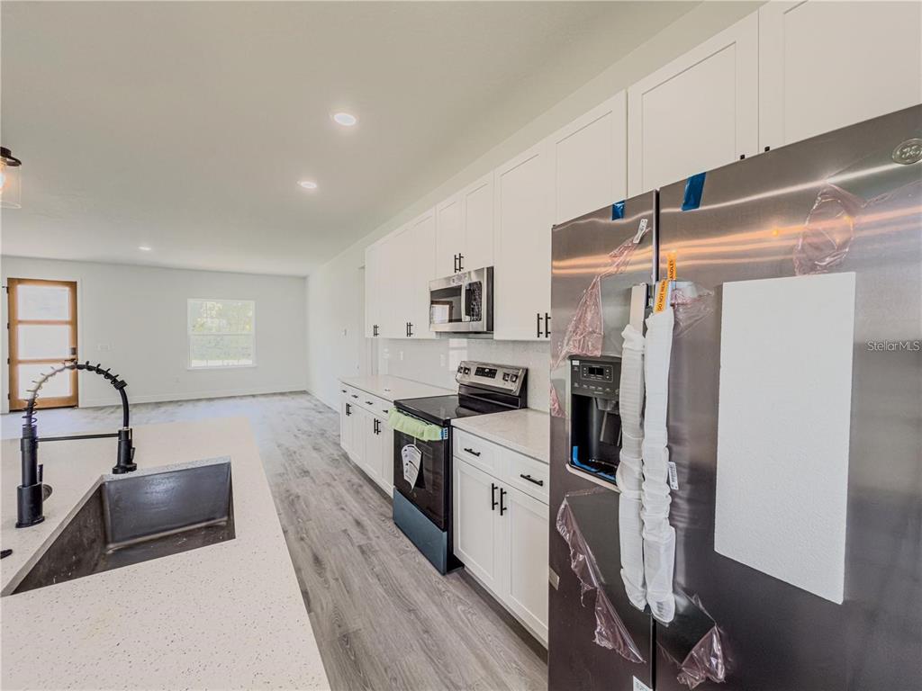 14245 Southwest 28th Court Ocala, FL 34473 - Photo 35 of 84 a kitchen with stainless steel appliances granite countertop a refrigerator a stove and a sink with wooden floor