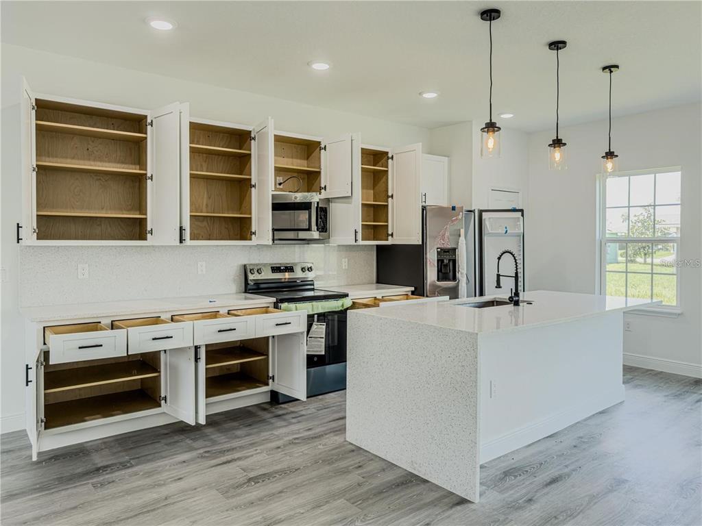 14245 Southwest 28th Court Ocala, FL 34473 - Photo 39 of 84 a kitchen with stainless steel appliances a stove a refrigerator a oven and white cabinets with wooden floors