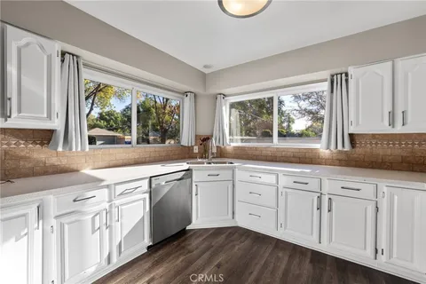 a kitchen with white cabinets and wooden floors