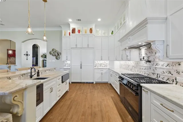 a large kitchen with stainless steel appliances granite countertop a lot of counter space and wooden floors