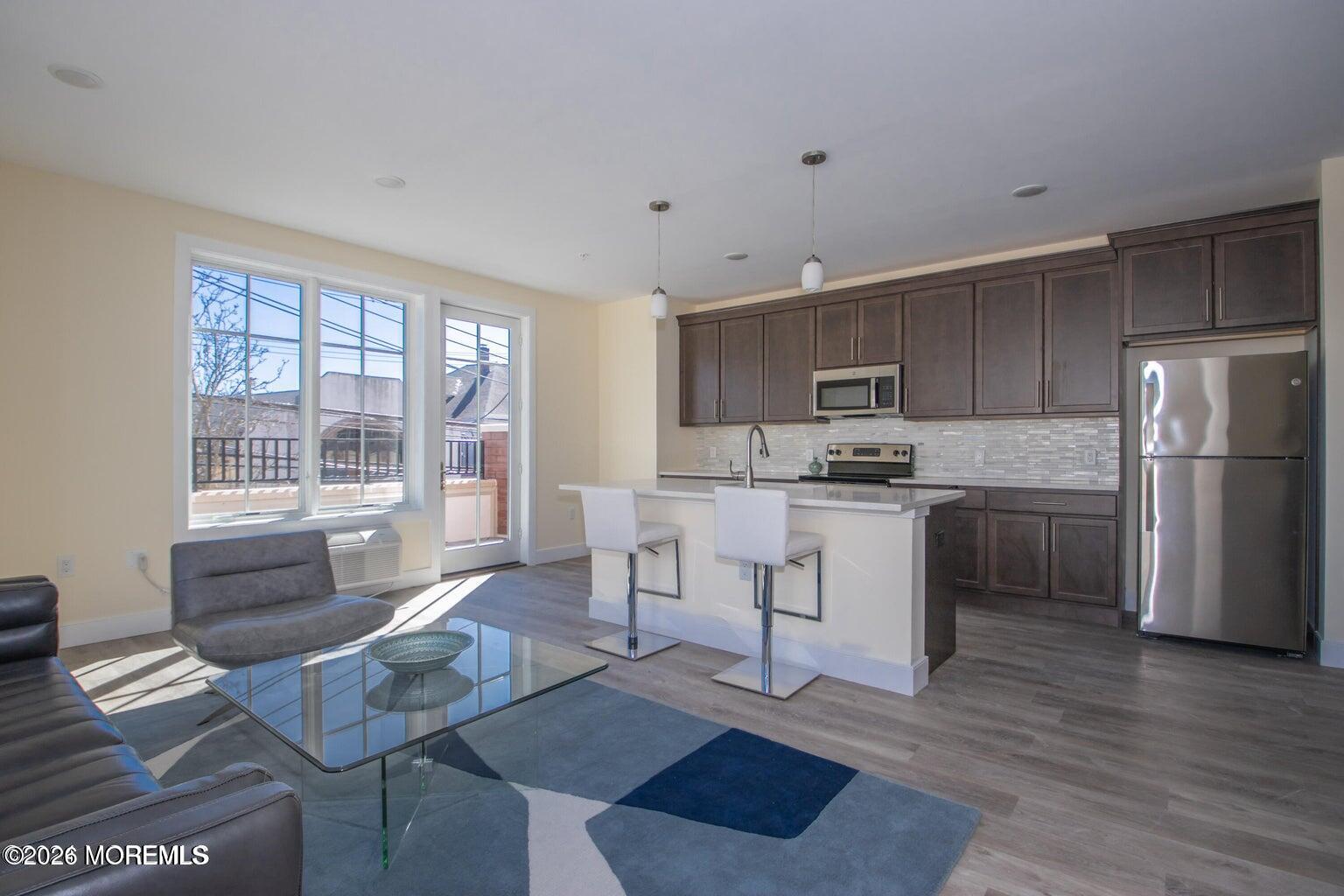 126 Main Street, Unit 311 Matawan, NJ 07747 - Photo 3 of 13 a kitchen with stainless steel appliances granite countertop a stove a refrigerator a sink a dining table and chairs with wooden floor