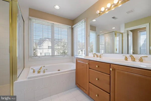 a bathroom with a tub sink double vanity granite and mirror
