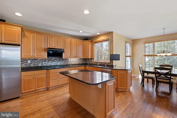 a kitchen with stainless steel appliances granite countertop wooden floor sink stove and granite counter top