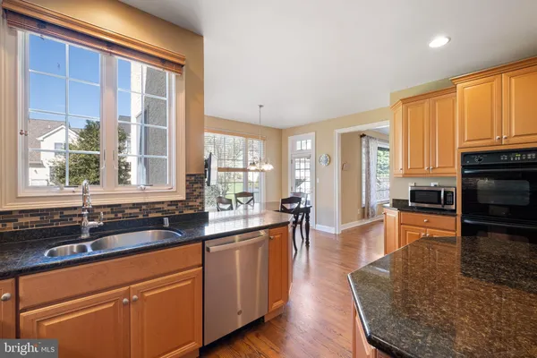 a large kitchen with kitchen island granite countertop a large window and stainless steel appliances