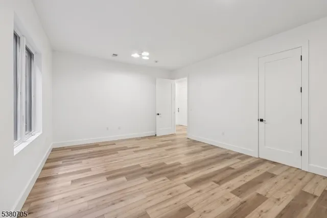 a view of empty room with window and wooden floor