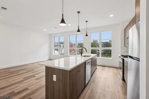 a large kitchen with stainless steel appliances a large counter top a stove and a refrigerator