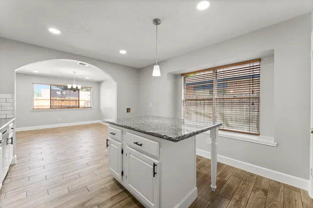 a kitchen with stainless steel appliances granite countertop a stove a sink and a refrigerator with wooden floors