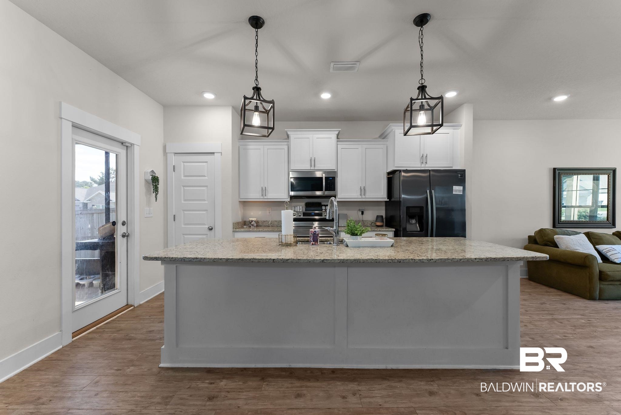 16607 Prado Loop Loxley, AL 36551 - Photo 13 of 46 Modern kitchen featuring a large central island with a light-colored countertop, white cabinetry, and stainless steel appliances