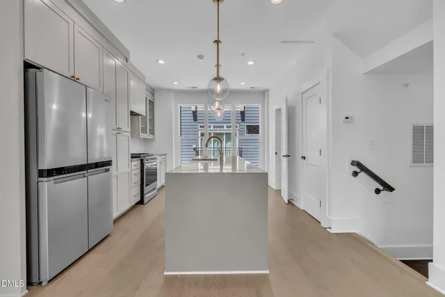 a view of a kitchen with refrigerator and wooden floor