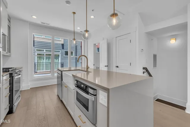 a kitchen with stainless steel appliances granite countertop a sink a stove and a wooden floors
