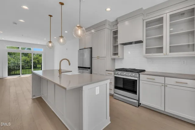 a kitchen with stainless steel appliances granite countertop a sink a stove and a wooden floors