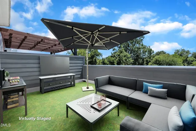 a view of a roof deck with couches under an umbrella