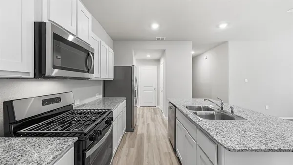 a kitchen with stainless steel appliances granite countertop a sink a refrigerator a stove a microwave and cabinets