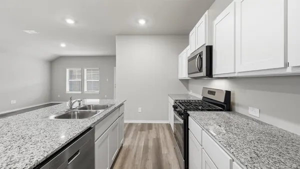 a kitchen with granite countertop a sink stove and refrigerator
