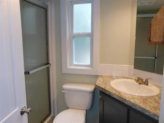 a bathroom with a granite countertop sink toilet and a mirror
