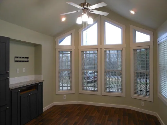 a view of an empty room with window and wooden floor