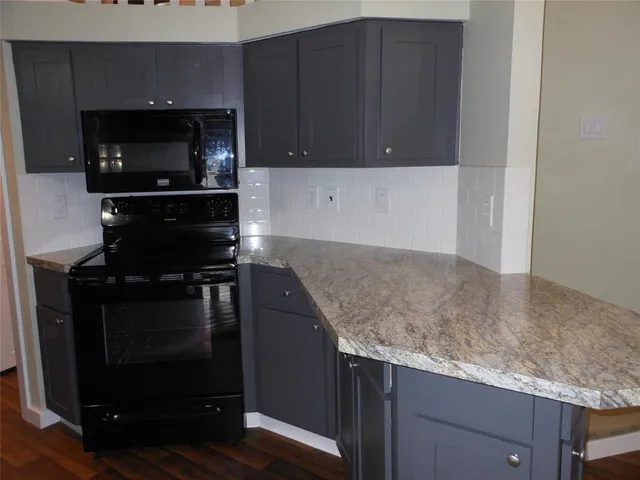 a kitchen with granite countertop white cabinets and black appliances