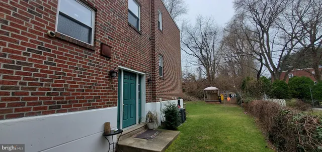 a backyard of a house with wooden fence and a large tree