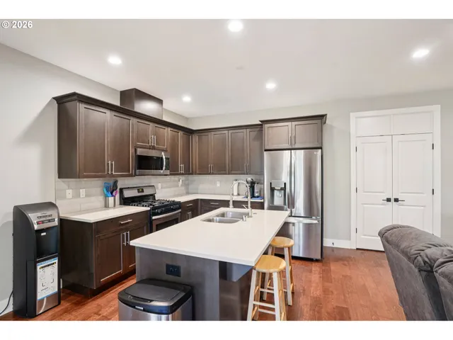 a kitchen with kitchen island a appliances a sink cabinets and wooden floor