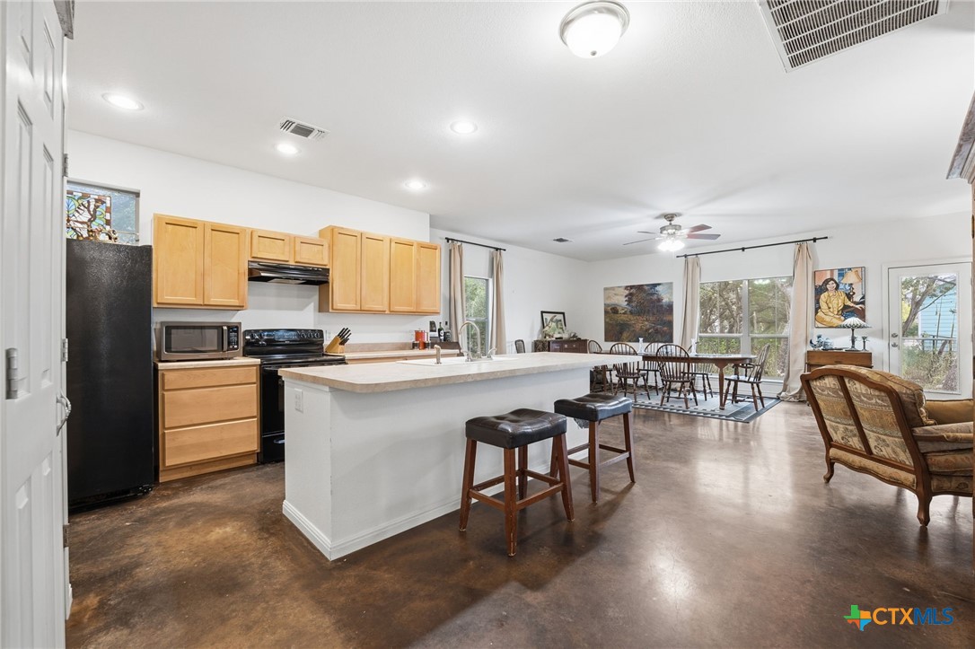 3075 Rustler Canyon Lake, TX 78133 - Photo 8 of 48 a kitchen with stainless steel appliances kitchen island granite countertop a refrigerator a stove a dining table and chairs with wooden floor