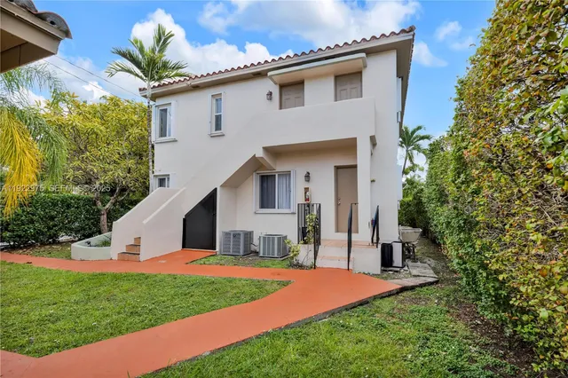 a view of a house with a small yard and large trees