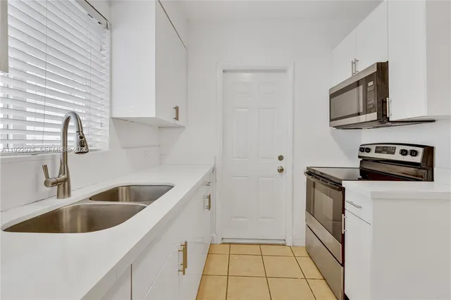 a kitchen with white cabinets a sink and a stove with wooden floor
