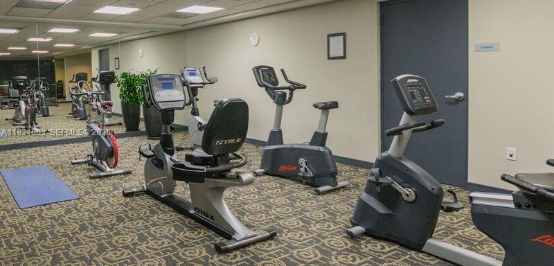 901 Brickell Key Boulevard, Unit 705 Miami, FL 33131 - Photo 37 of 41 a room with gym equipment and mirror
