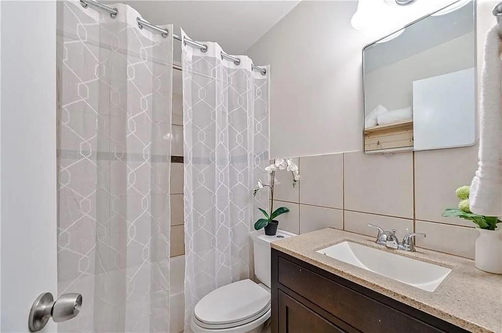 260 River Valley Road Northwest Atlanta, GA 30328 - Photo 15 of 20 a bathroom with a granite countertop sink toilet a mirror a shower and a sink