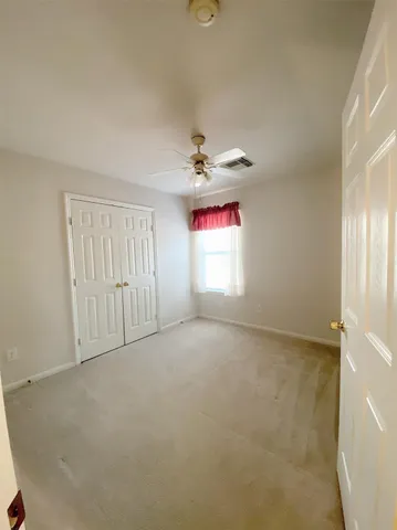 an empty room with windows and fan