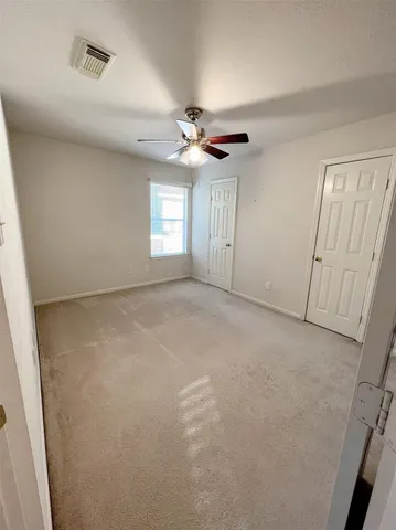 an empty room with windows and fan